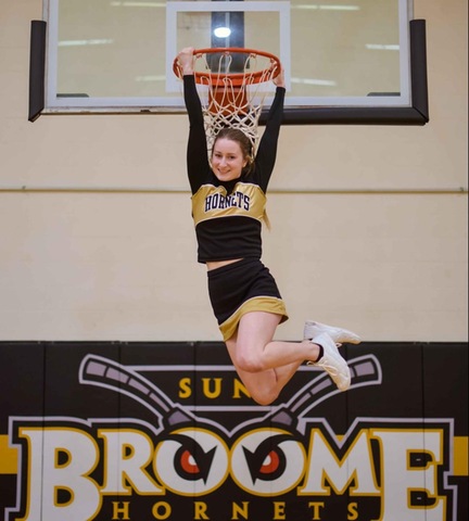 Cheerleader holding on to basketball rim