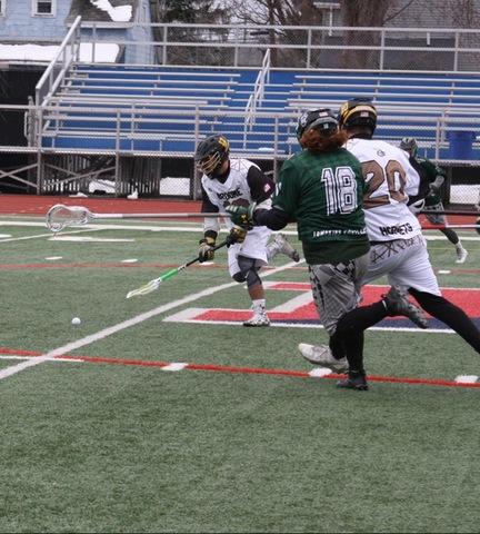 SUNY Broome lacrosse player picking up ball off turf