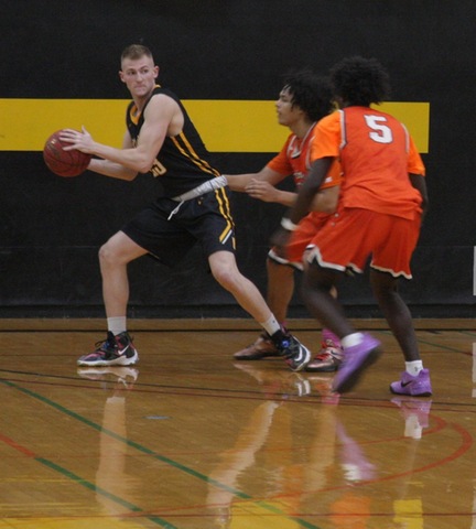 SUNY Broome men's basketball player looking to make a pass over two defenders