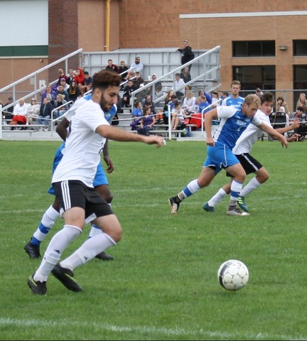 Men's soccer players from both teams chasing ball