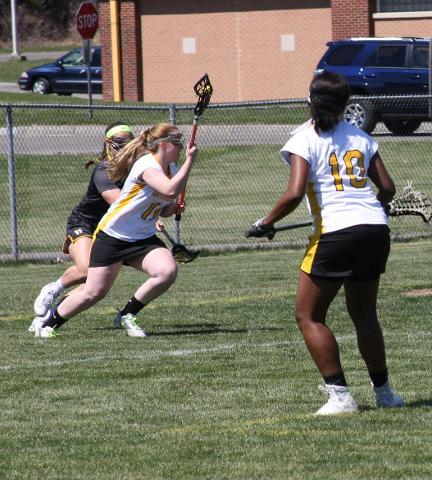 SUNY Broome women's lacrosse player running down field with ball
