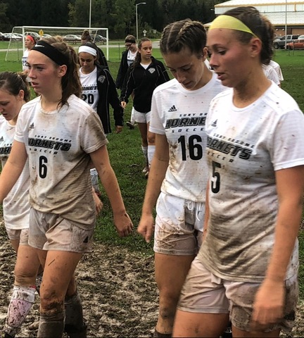 Players covered in mud coming off field