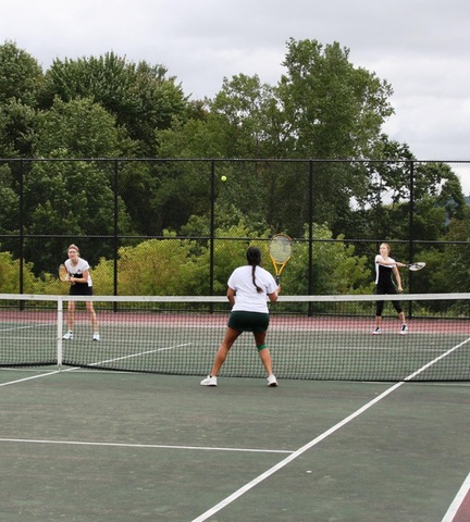 SUNY Broome women's tennis player returning serve in doubles match