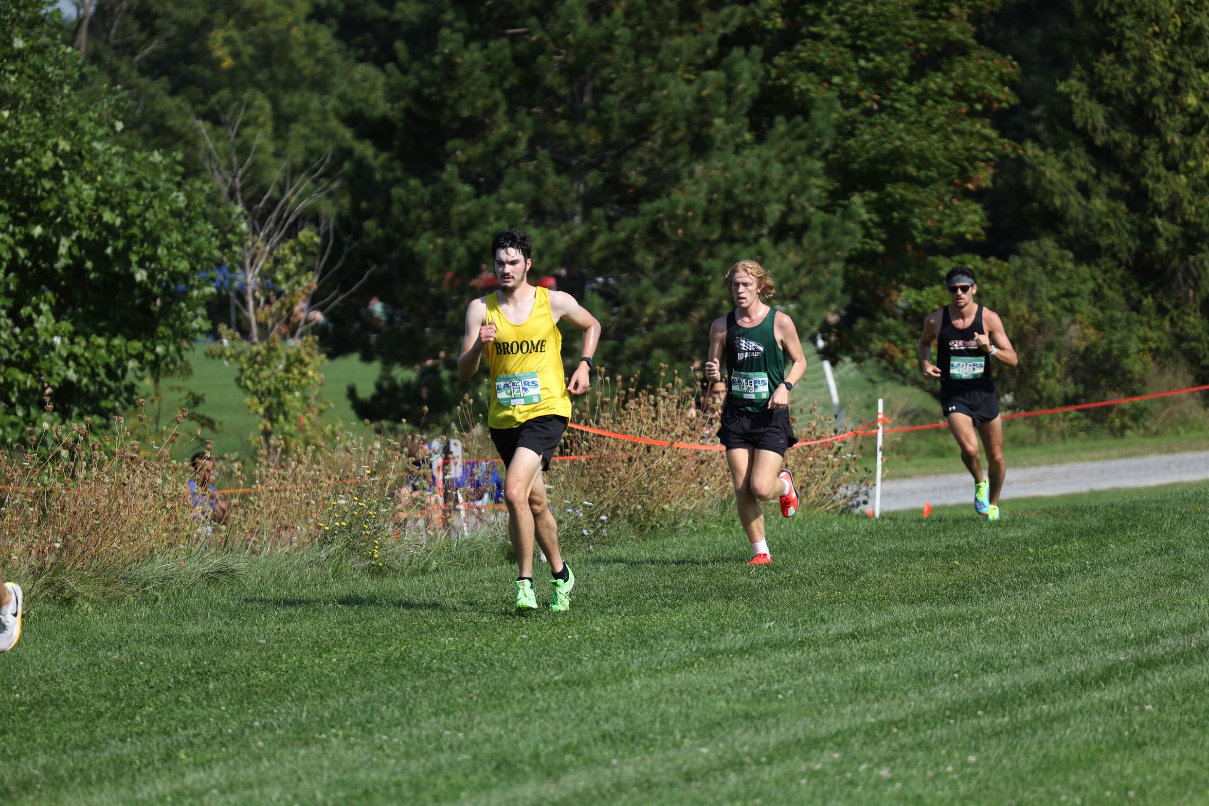 Broome cross country runner leads two opposing runners on the course